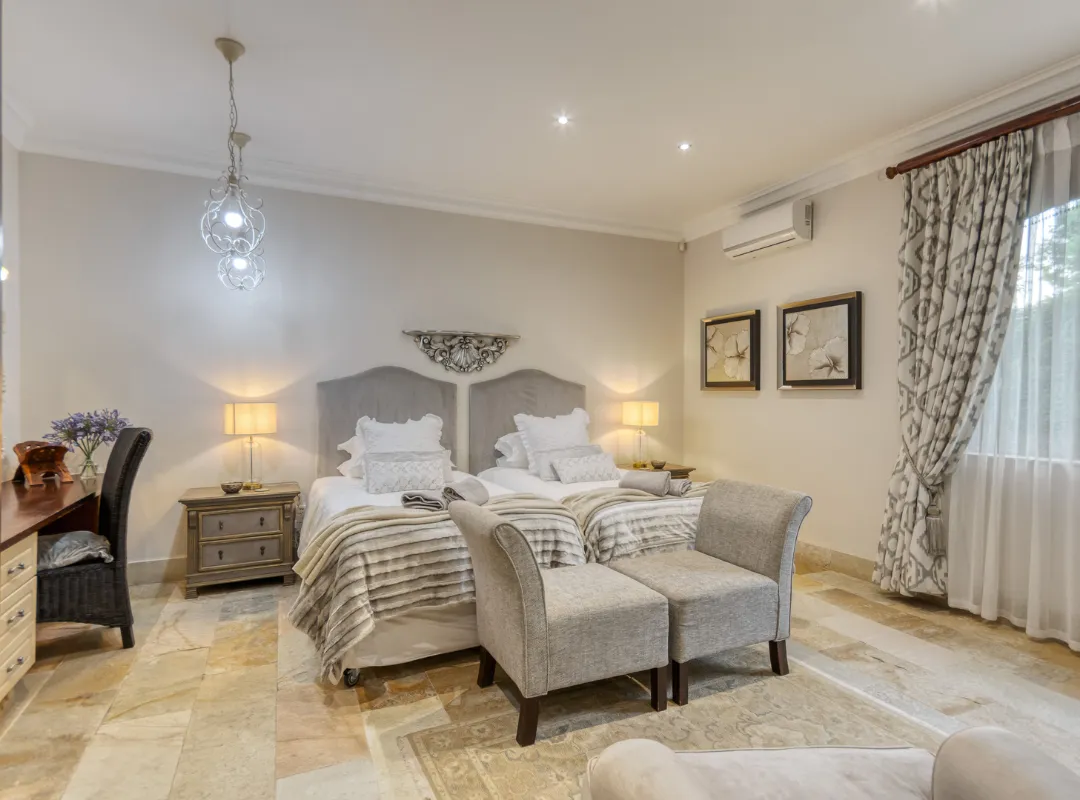 A luxurious bedroom in the La Lavande room at Bonne Chance estate, featuring a bed, chair, dresser, and mirror.